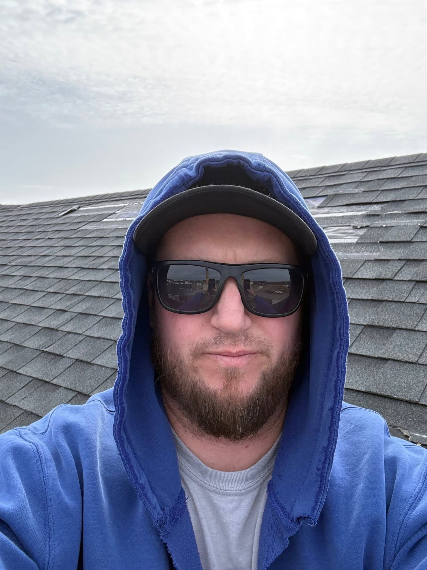 Curtis Rolle in a blue hoodie and sunglasses on a wind-damaged roof