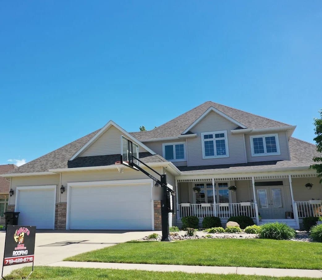 A Rolle's Home Improvements roofing yard sign in front of a two-story home with a new roof
