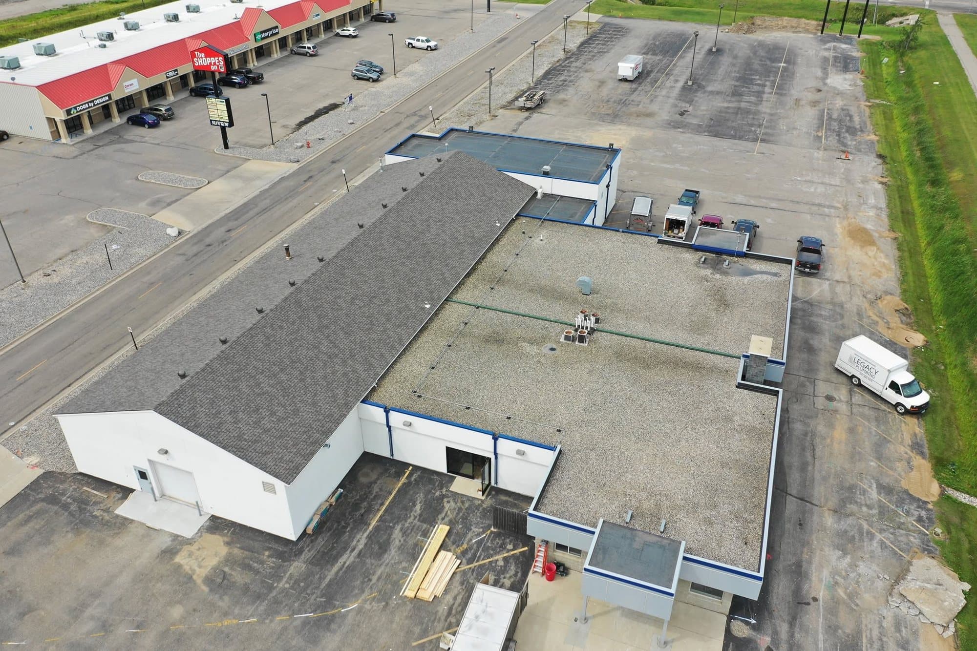 Commercial building with its newly shingled pitched roof section, seen from the air