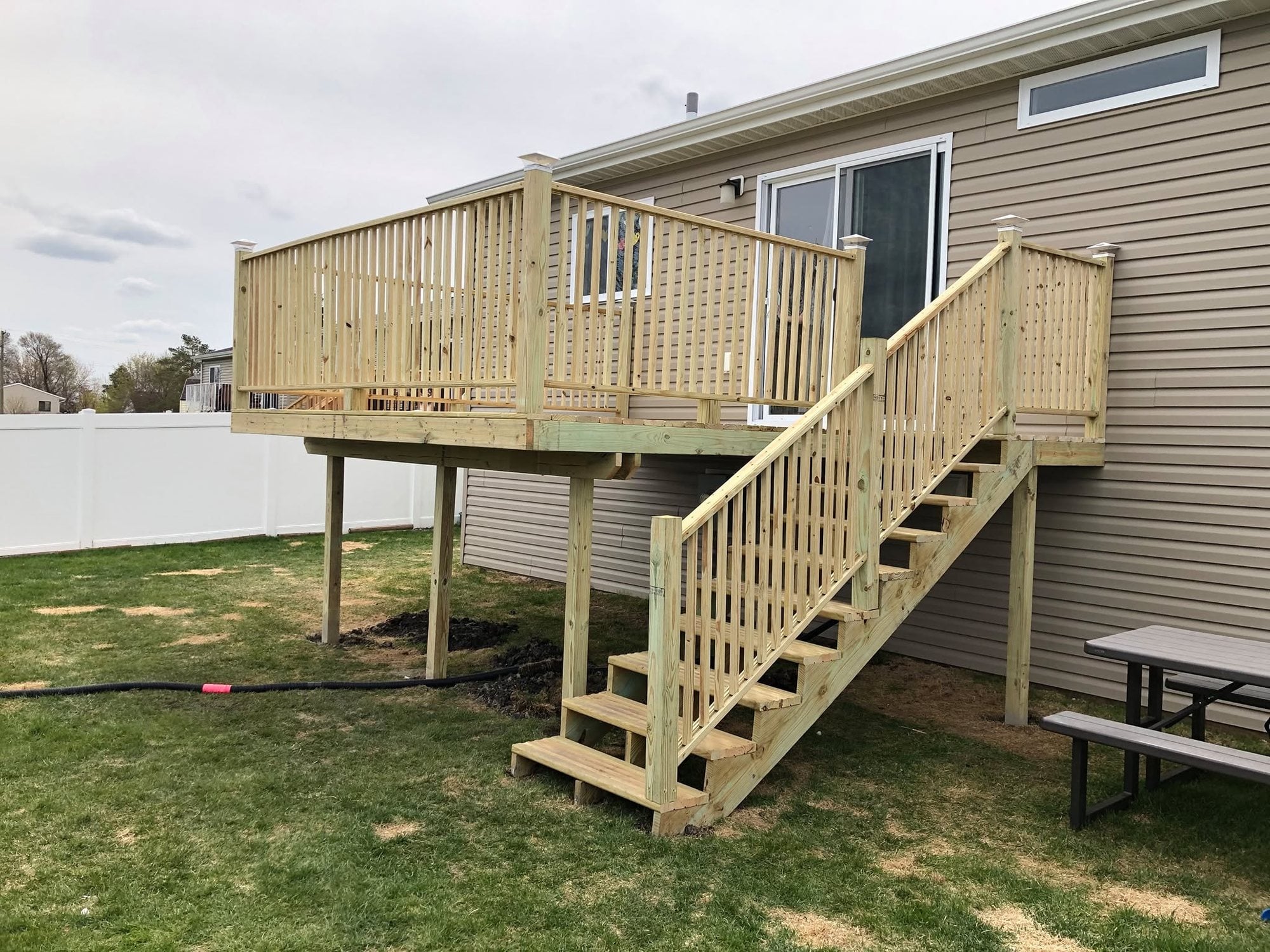 New second-story treated-lumber deck with stairs down to the yard