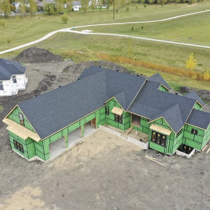 New build wrapped in green sheathing with a fresh dark shingle roof
