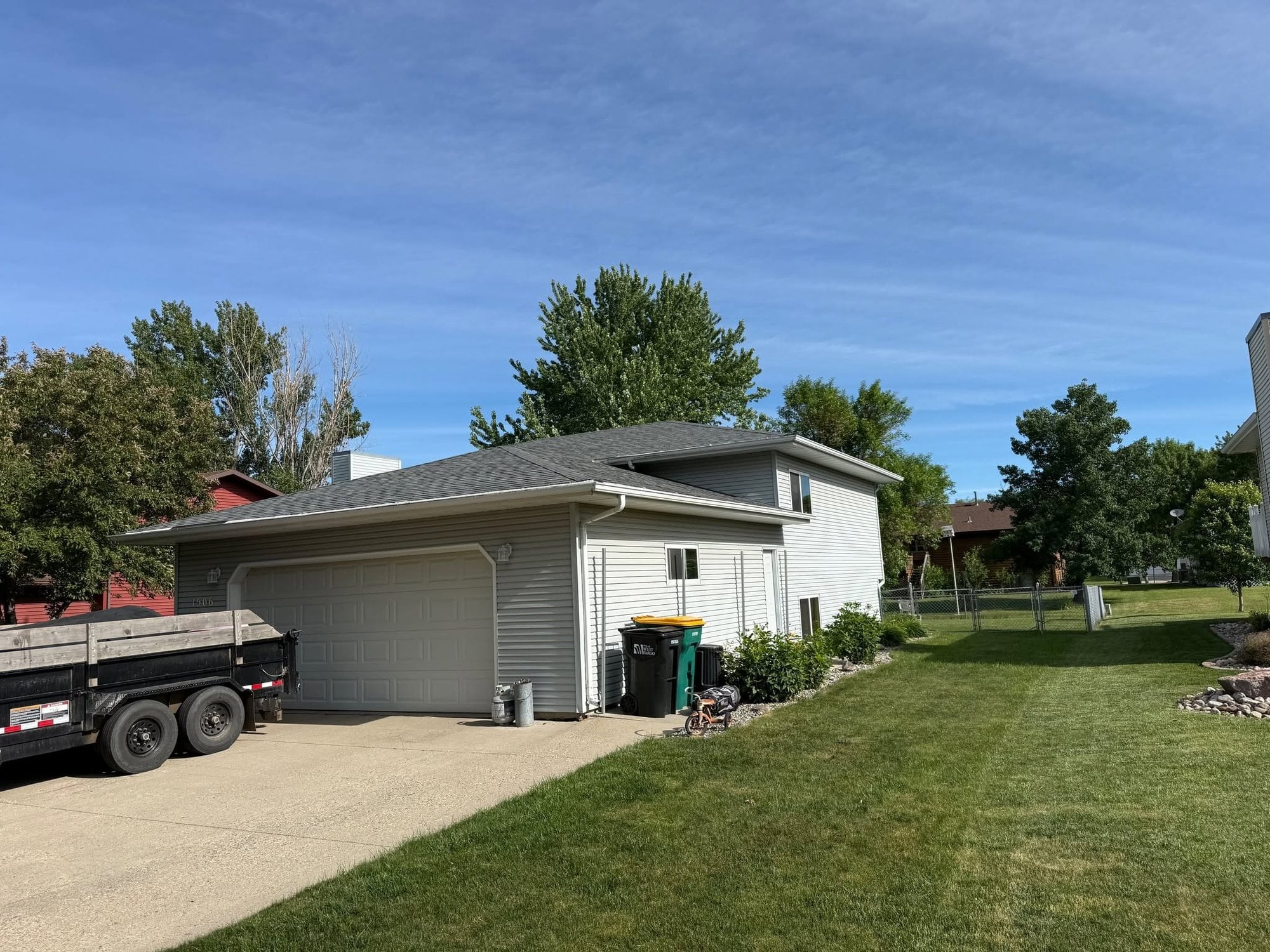Two-story home with a new charcoal roof and the dump trailer in the driveway