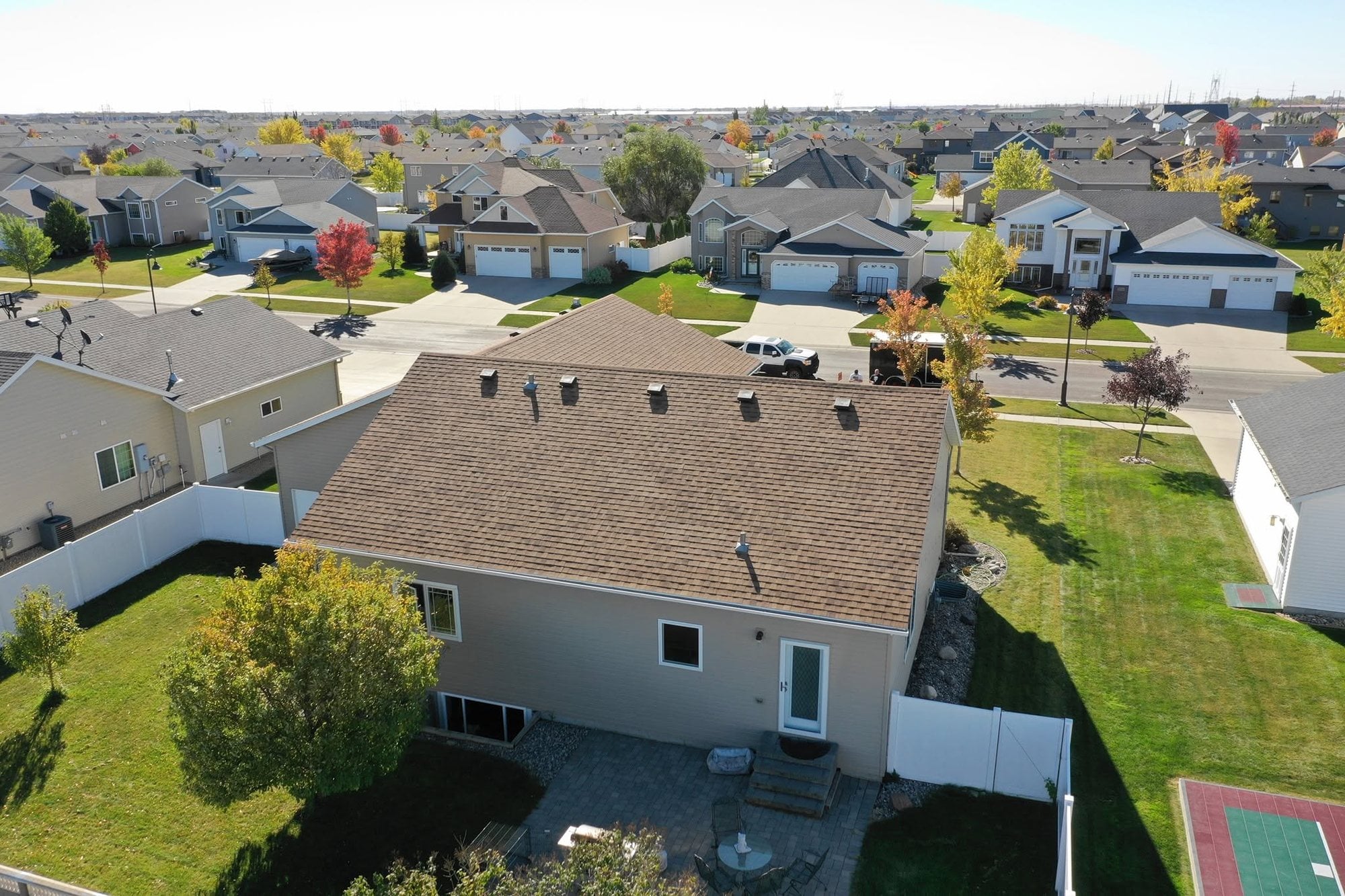 Home with repaired tan vinyl siding and a new roof after a storm