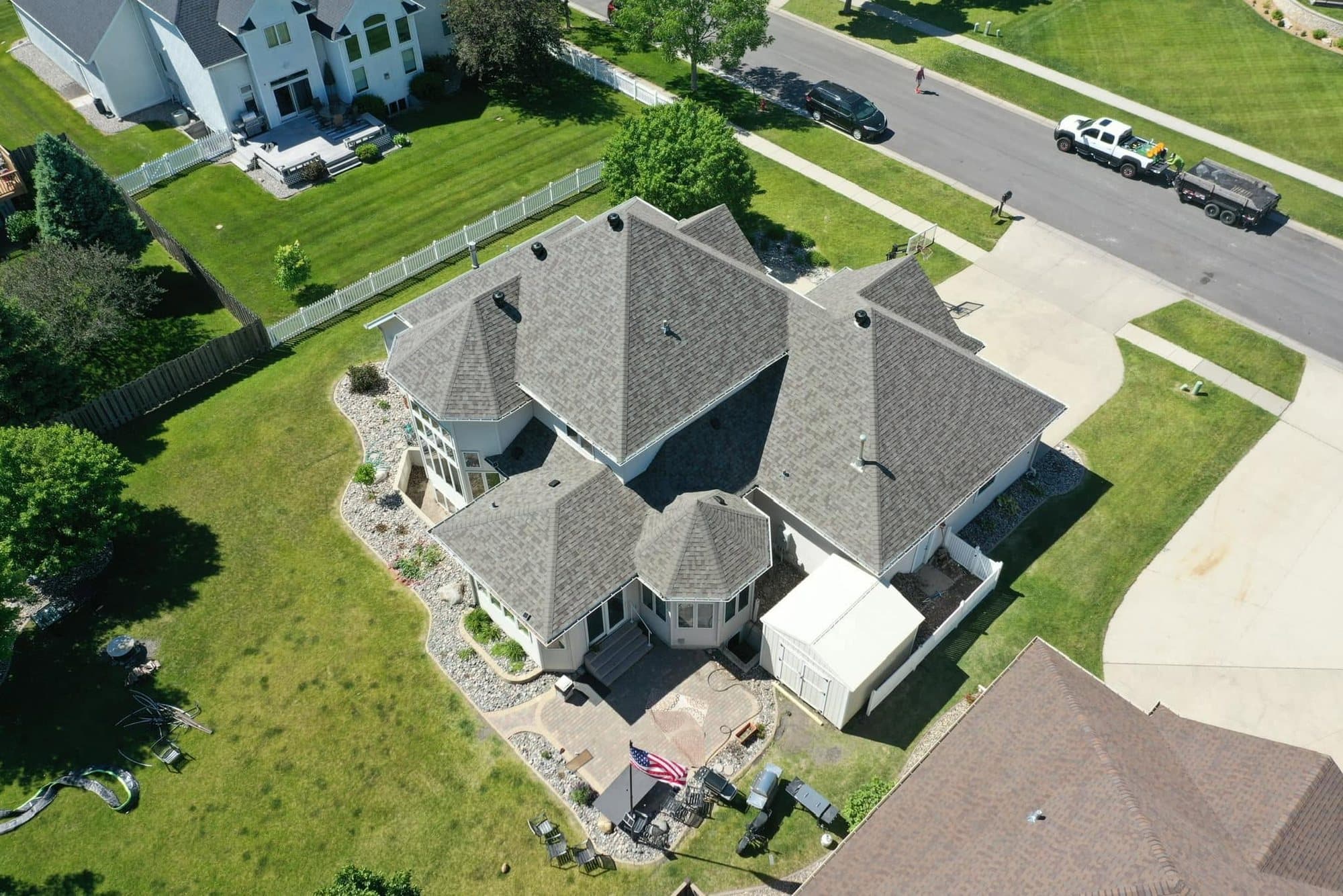 Large two-story home with a turret and a new gray shingle roof, seen by drone