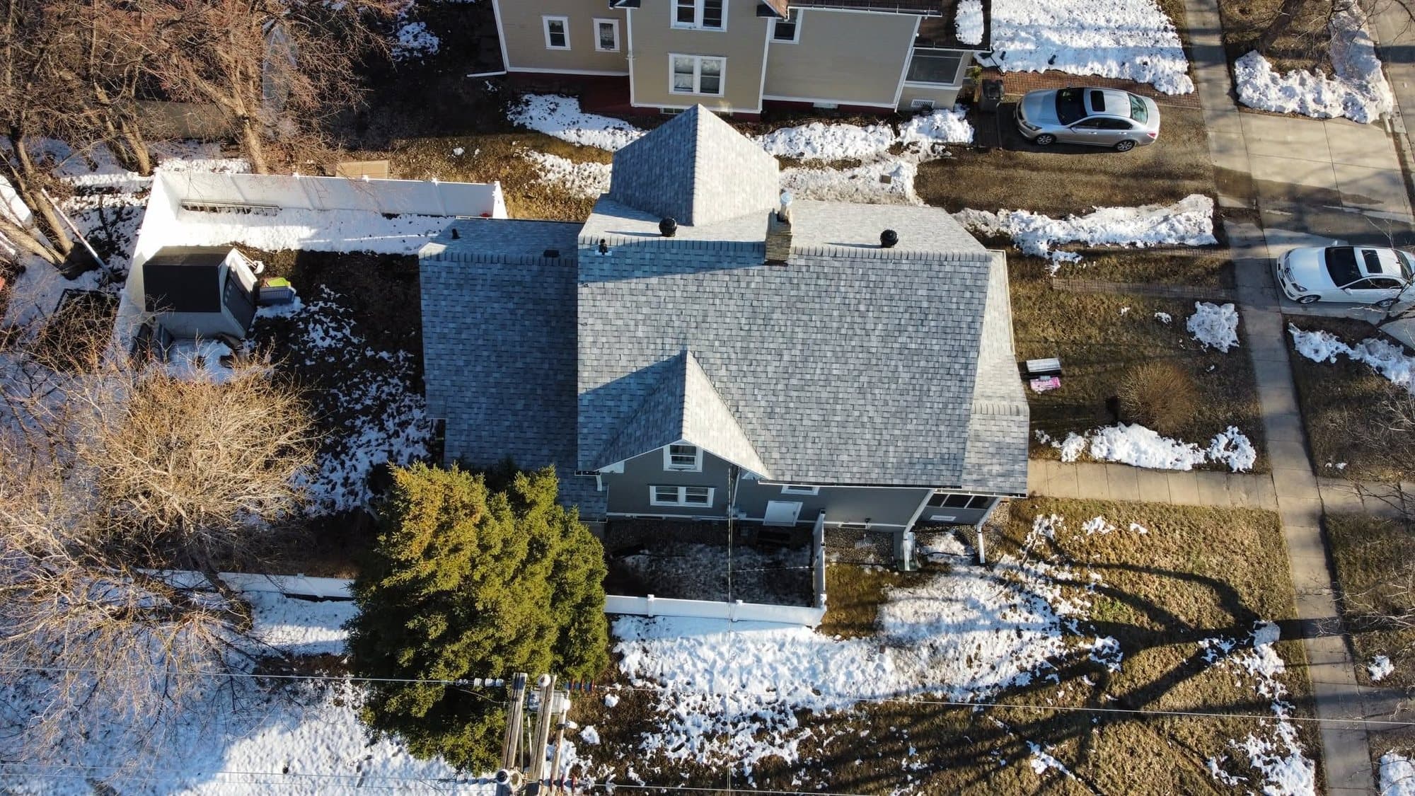 Aerial view of a two-story home with a new gray roof in late winter